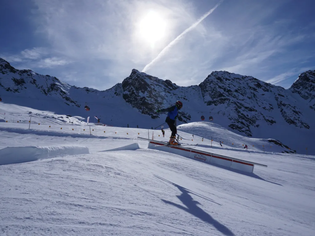 Skifahrer auf der Piste vor der Bergkulisse in der Sonne.